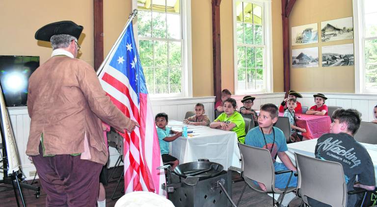 A Revolutionary War reenactor presents to children.