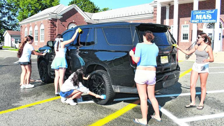 Members of the Sparta girls' tennis team wash a car.
