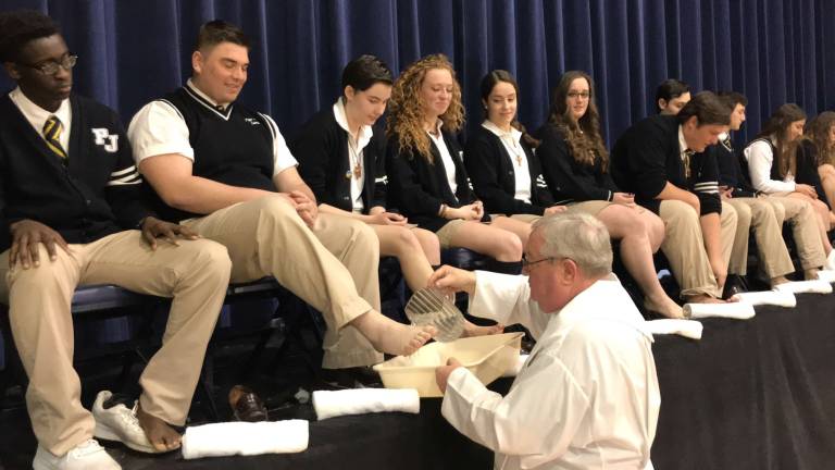 Pope John XXIII Regional High School senior Nick Bello, second from left, has his feet washed by Pope John President and Principal Rev. Msgr. Kieran McHugh during the 2018 Service Awards Liturgy at Pope John in Sparta Photos by Anthony Spaulding