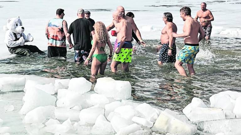 People wade into the water.