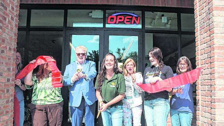 Greene’s Beans Cafe owner Kelsey Walter, center, cuts the ribbon.