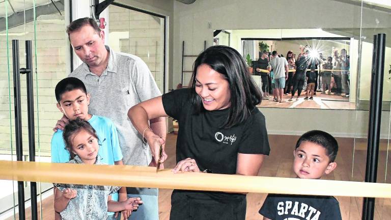 Rebecca Sarnicola of the Sparta Wellness Collective cuts the ribbon as her family looks on.