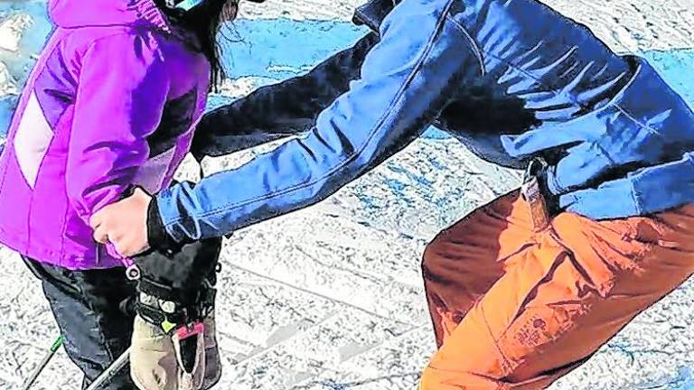 <b>Cory Gorczycki helps a child on the ski slopes.</b>